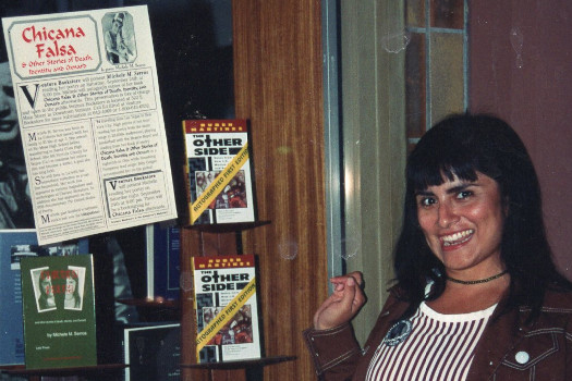 Serros next to store front window where 'Chicana Falsa' book is displayed.